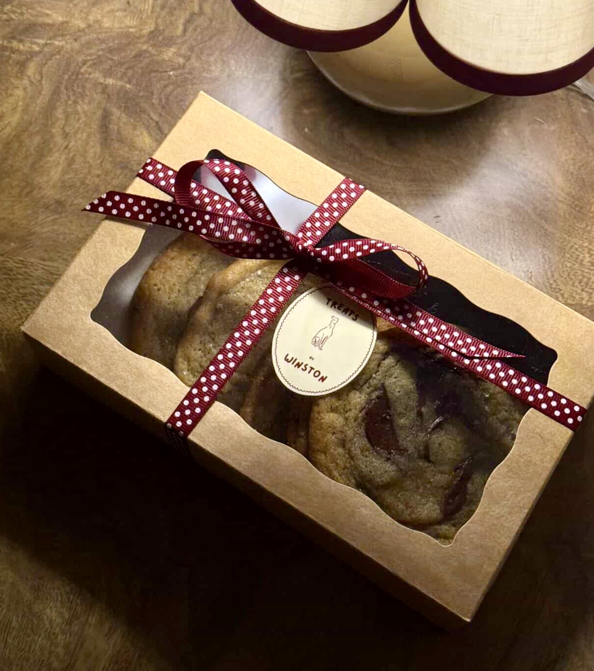 A Treats by Winston cookie box tied with a ribbon and branded tag.