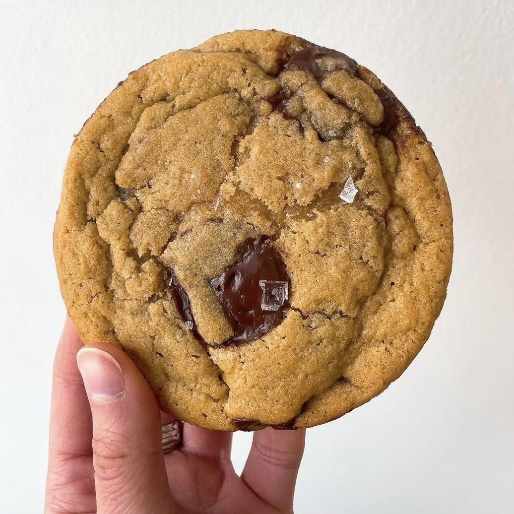 The Winston cookie held in hand, molten chocolate and flaked salt on top.